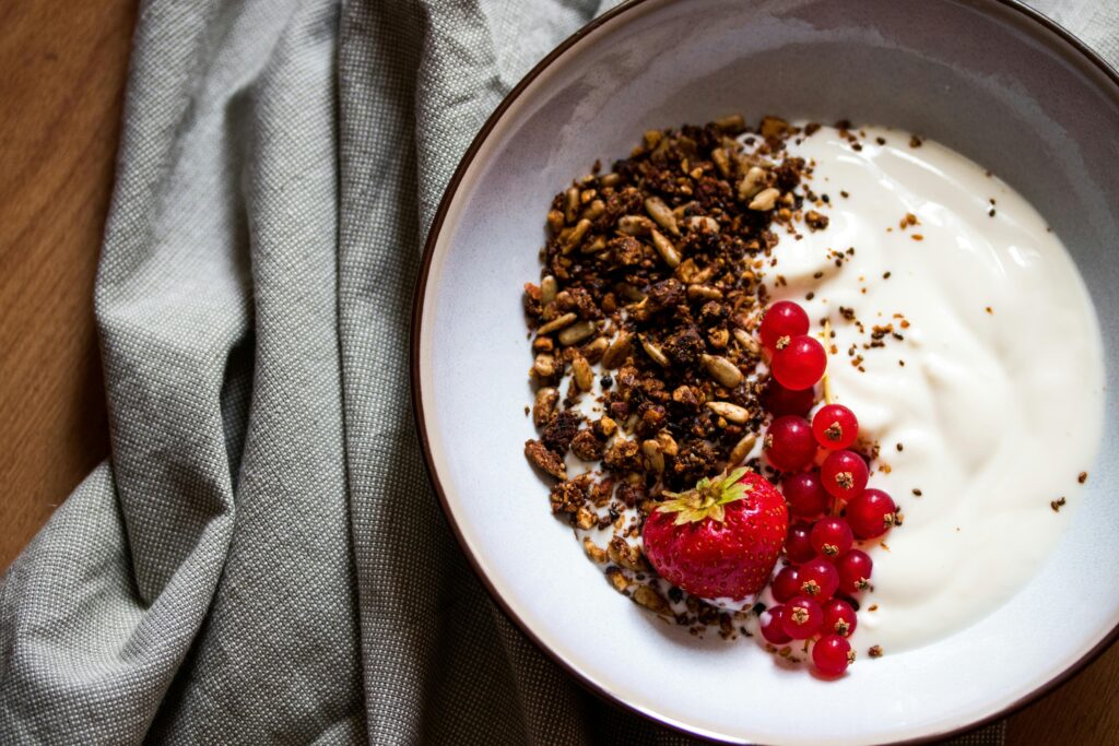 Delicious breakfast bowl featuring yogurt, granola, strawberry, and red currants, perfect for a healthy start.